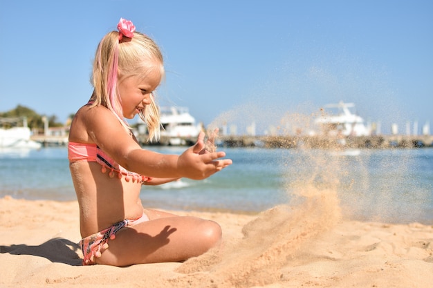 Fille jouant avec du sable sur la plage près de la mer