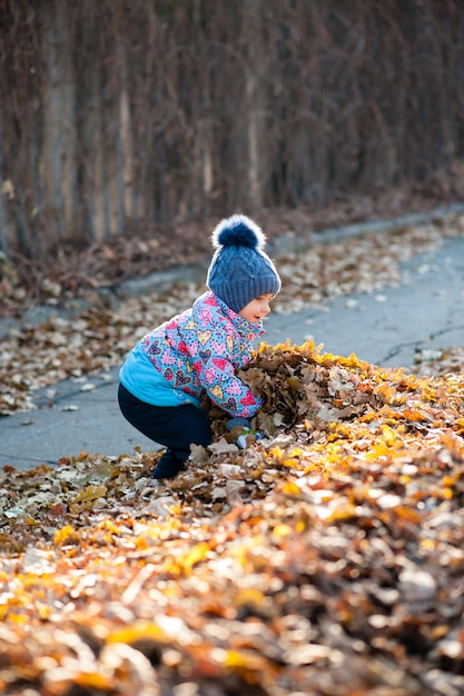 Fille jouant avec des feuilles dans le parc