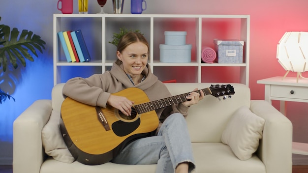 Fille jouant de la guitare acoustique à la maison Musicienne apprenant à jouer d'un instrument de musique dans la vie