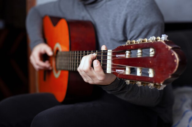 Fille jouant d'une guitare acoustique à six cordes avec des cordes en nylon.