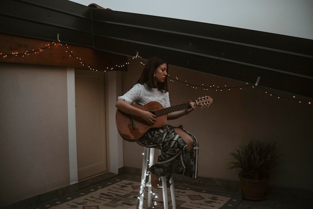 Photo une fille jouant de la guitare sur la terrasse.