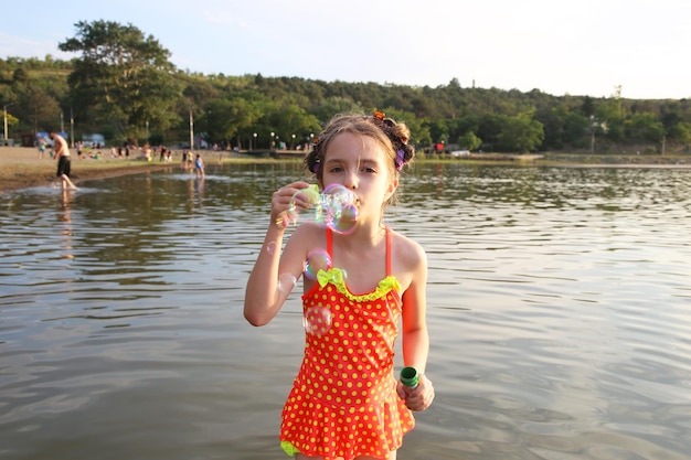 fille jouant sur le lac avec des bulles de savon