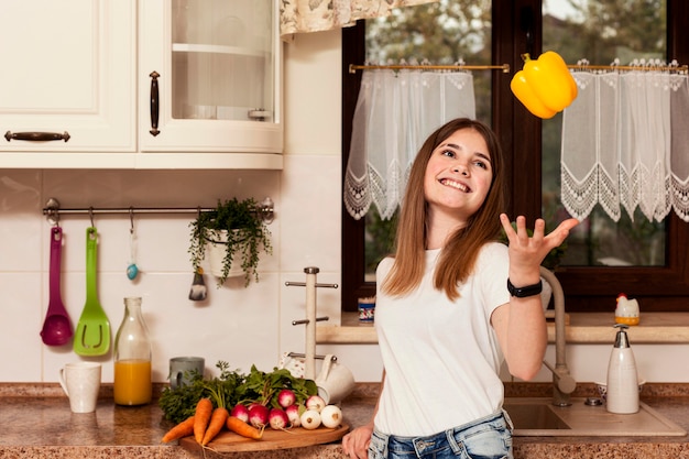 Fille jouant avec des légumes dans la cuisine avant le dîner