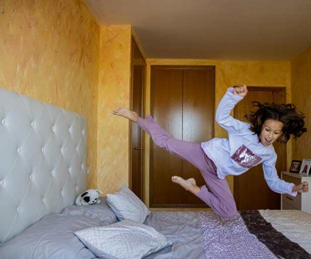 Une fille jouant sur le lit à la maison.