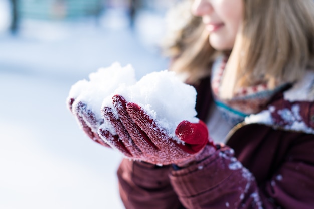 Photo fille jouant avec de la neige dans le parc. portrait de la fille heureuse portant des vêtements d'hiver enneigés