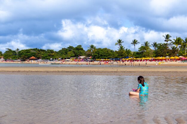 Une fille jouant sur la plage avec du sable et de l'eau de mer