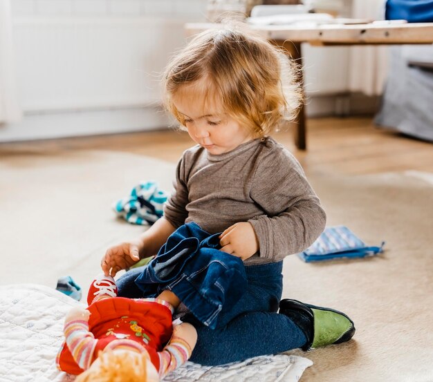 Photo une fille jouant avec une poupée alors qu'elle est assise à la maison.