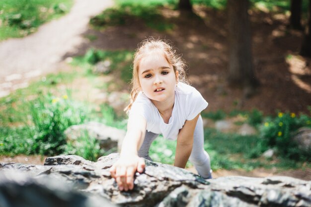 Fille jouant sur des rochers, escalade, enfance et joie, jouer avec d'autres enfants, développement