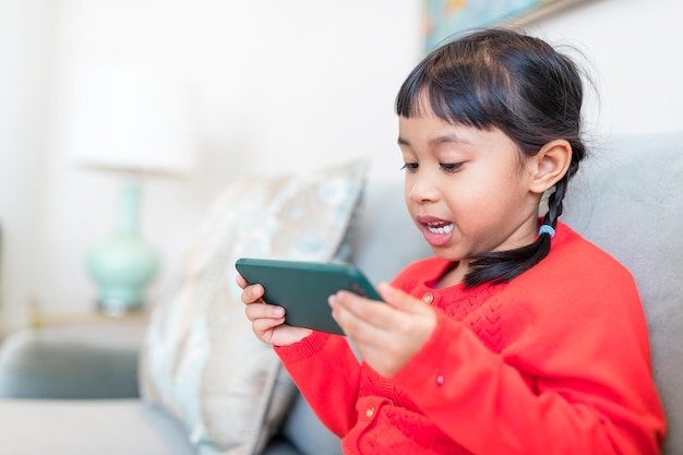 Fille jouant sur le téléphone portable à la maison