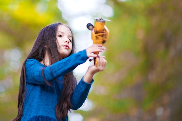 Une fille joue avec un avion jouet dans le parc