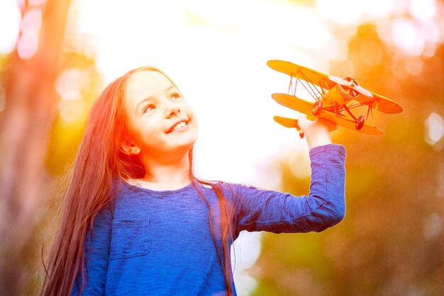 Une fille joue avec un avion jouet dans le parc