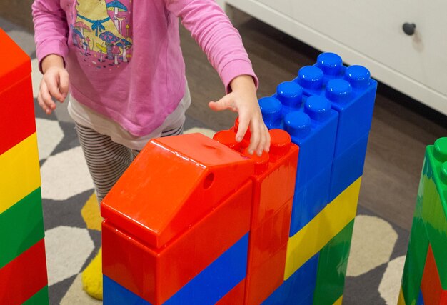 une fille joue avec des blocs dessinés d'un constructeur à la maison