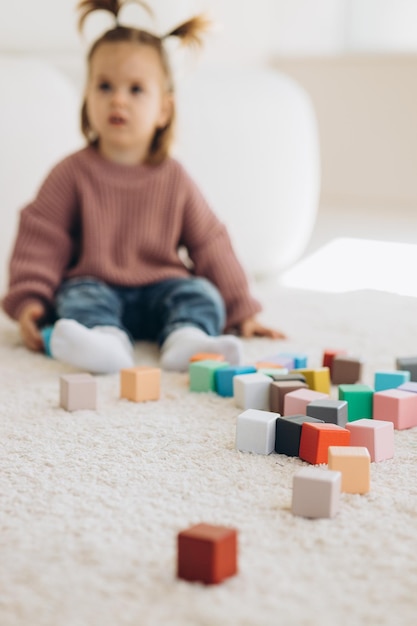 Photo fille joue des jouets dans le salon jouet en bois montessori pyramide pliée cercle triangle rectangle éléments en bois de jouets pour enfants jouet coloré bleu jaune rouge vert