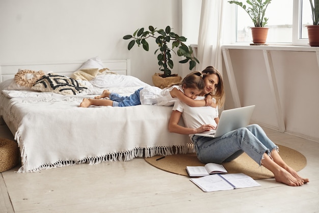 Fille joue avec maman et chat pendant que maman travaille sur ordinateur