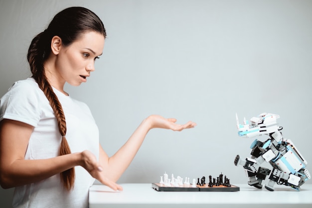 Une fille joue avec un robot aux échecs.