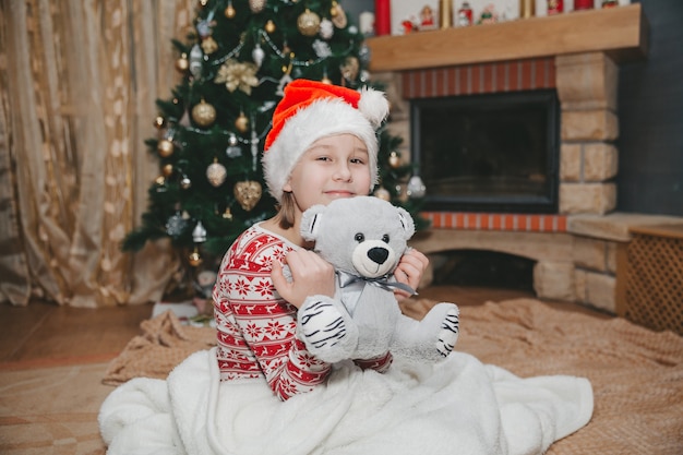 Fille et jouet à l'arbre de Noël dans le salon