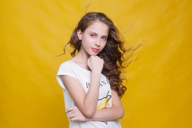 Fille joyeuse avec de beaux cheveux brune sur fond jaune