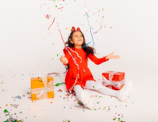 Fille joyeuse avec boîte-cadeau à la fête avec des confettis tombant sur elle. anniversaire ou fête du nouvel an