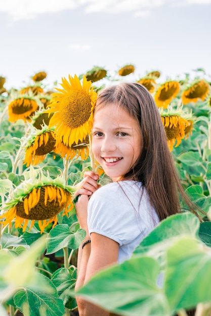 Une fille joyeuse embrasse un tournesol dans un champ au soleil Tourisme local et liberté