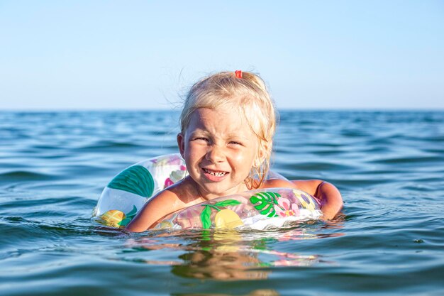 Une fille joyeuse nage dans la mer avec un anneau gonflable.