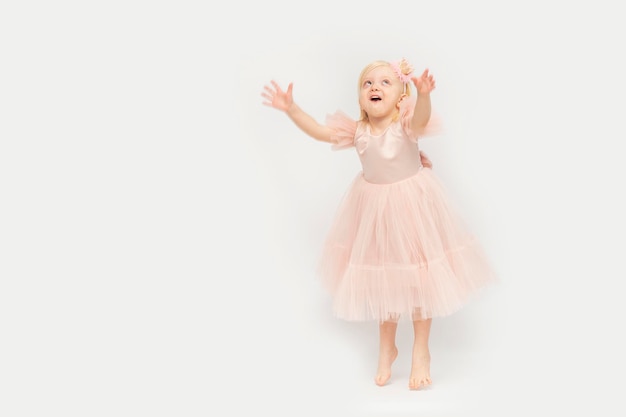 Fille joyeuse en robe de princesse festive se dresse sur les orteils Princesse blonde isolée sur fond blanc