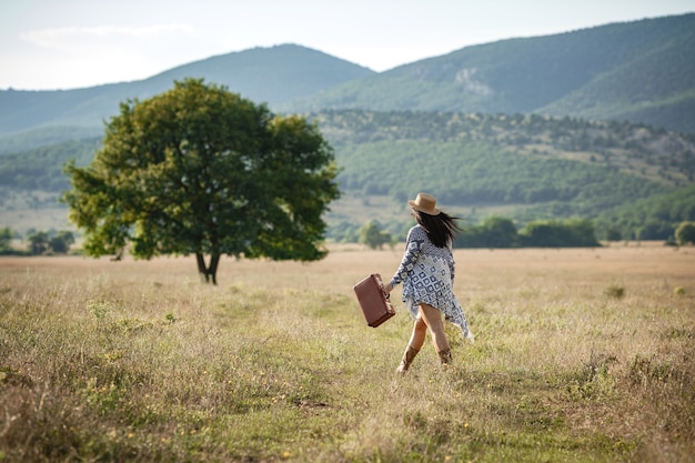 Photo une fille joyeuse souriante aux cheveux bouclés respire une poitrine pleine et jouit de la liberté, debout sur le terrain près du grand arbre seul.