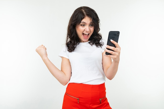 Fille joyeuse avec un téléphone dans ses mains sur un fond blanc avec espace de copie.