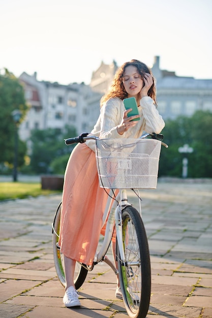 Fille en jupe pinky avec un vélo dans le parc