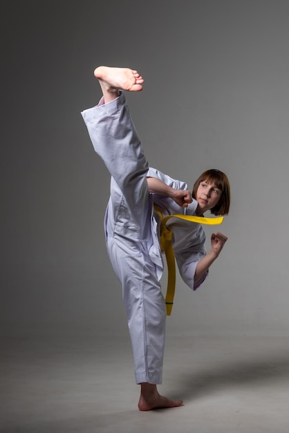Photo une fille de karaté s'entraîne dans un kimono avec des coups de poing et des coups de pied