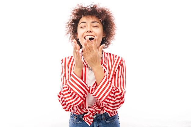 Une fille kazakhe chanceuse positive avec une coiffure afro en riant se réjouit de célébrer la victoire a entendu de bonnes nouvelles isolées sur fond blanc