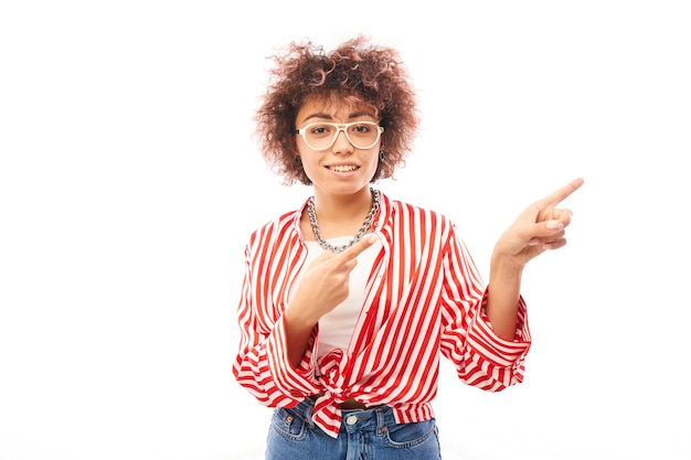 Fille kazakhe positive avec une coiffure afro pointe l'index à l'espace de copie isolé sur fond de studio blanc