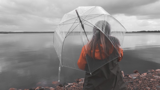 Fille sur le lac avec un parapluie par mauvais temps