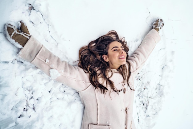 Fille de lancement jouant et s'étendant dans la saison d'hiver de neige