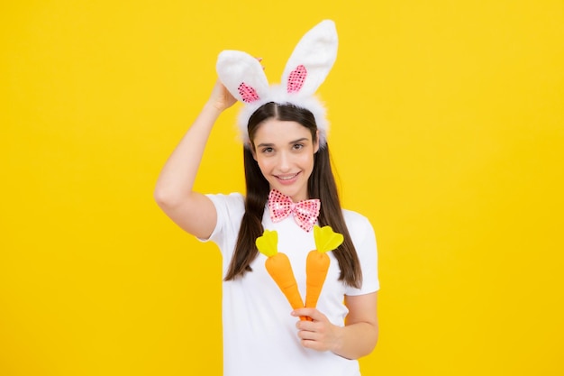 Fille de lapin avec carotte jouet Joyeuse fille souriante dans des oreilles de lapin célébrant Pâques