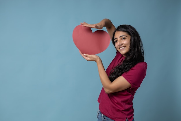 Fille latine mexicaine tenant un papier en forme de coeur rouge Saint Valentin