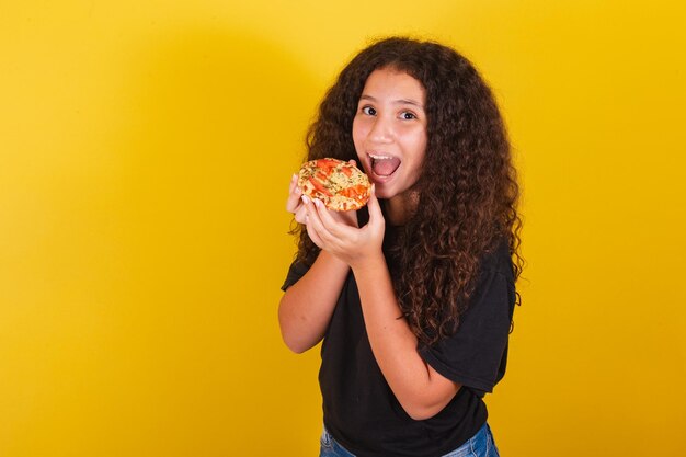 Fille latino-américaine brésilienne pour cheveux afro fond jaune se prépare à monder délicieuse mini pizza pizza margarita pizza fromage qui s'étend du fromage