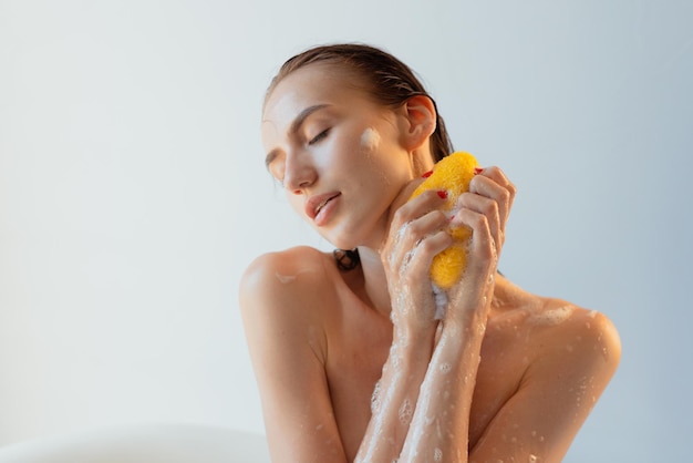 Fille lave son corps avec du gel douche et du shampoing avec gros plan de mousse