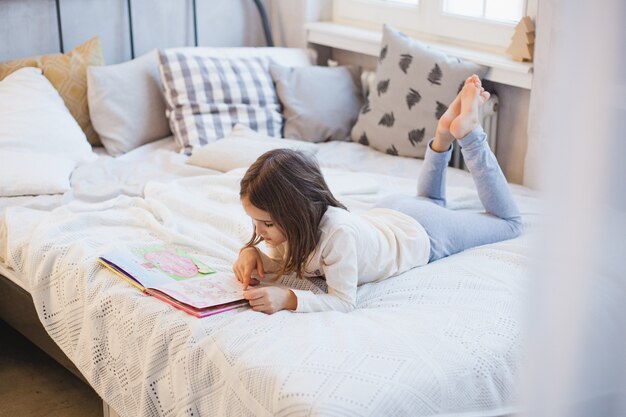 Fille lisant un livre sur le lit à Noël