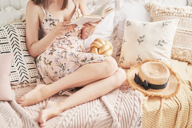 Fille lisant un livre à la maison sur un lit clair