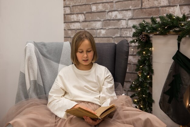 Une Fille Lit Un Livre Sur Une Chaise à Côté De La Cheminée, Flou Artistique