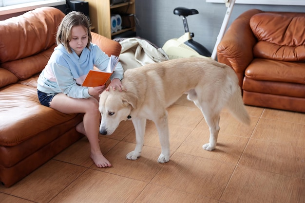 Photo une fille lit un livre avec un chien dans le salon