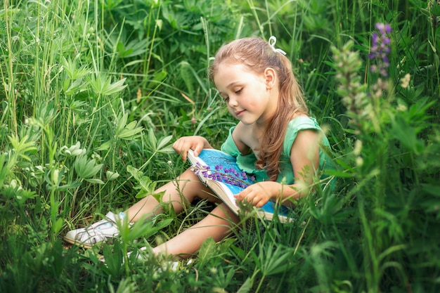 fille lit un livre dans la nature en été