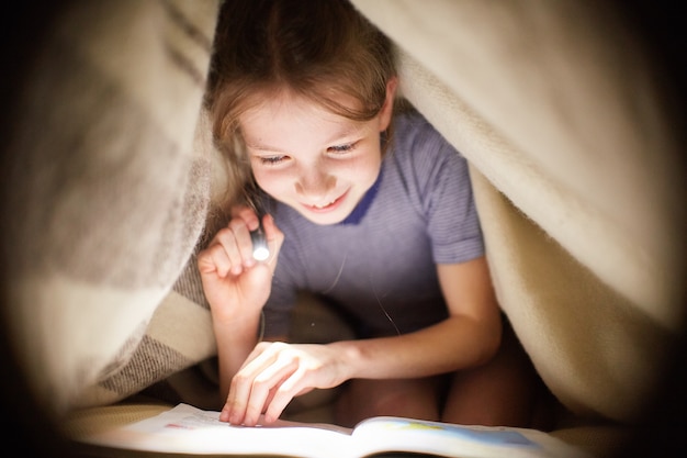 Fille Lit Un Livre Sous Une Couverture Avec Une Lampe De Poche Dans Une Pièce Sombre La Nuit