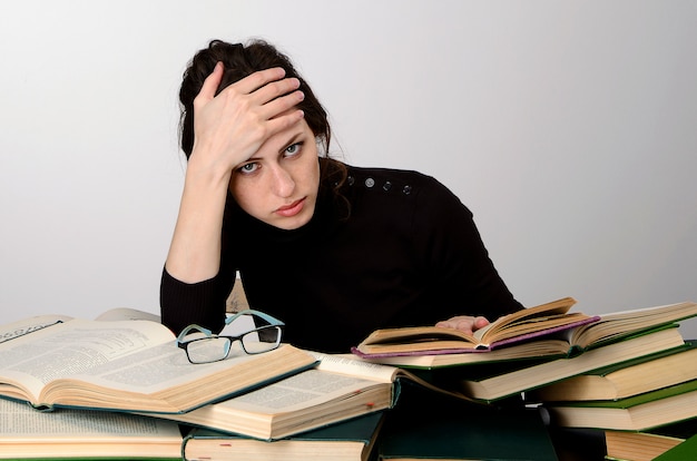 Fille livre examen difficultés pull noir enseigne à la table fatigué se réjouit des émotions