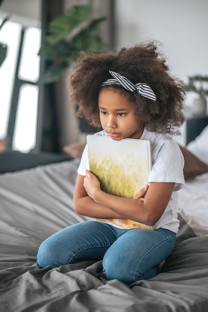 Fille avec un livre. Une fille assise sur un ned avec un livre dans les mains et à la réflexion