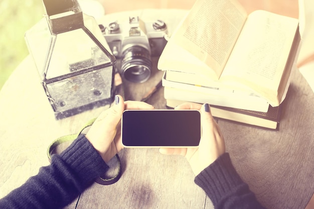 Fille avec des livres de téléphone portable vierges et un vieil appareil photo