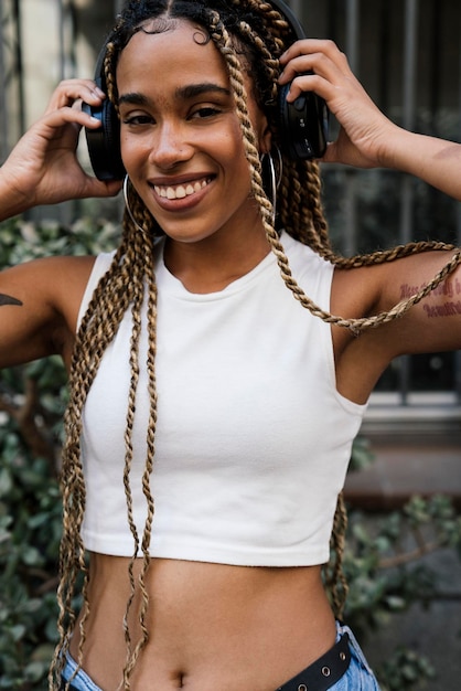 fille avec de longues tresses blondes écoutant de la musique avec des écouteurs et souriant à la caméra