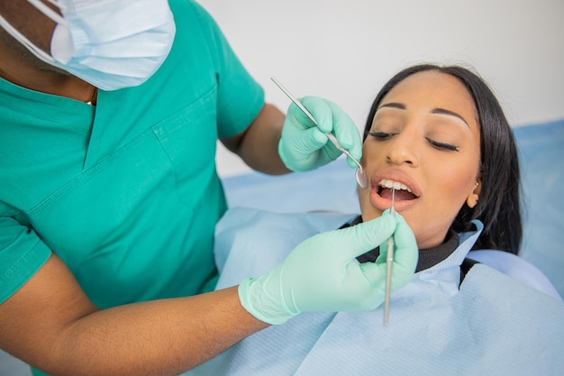 Fille lors d'une visite dentaire médecin avec des outils dentaires examine sa bouche