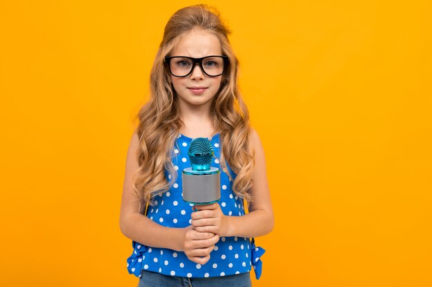 Fille à lunettes détient un microphone sur fond orange