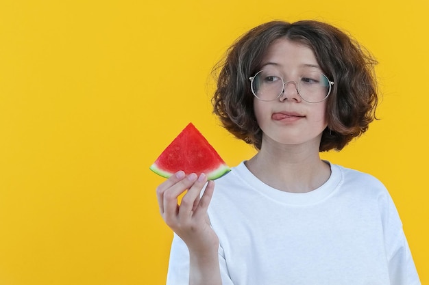 Fille avec des lunettes lèche ses lèvres et tient un morceau de pastèque mûre juteuse dans sa main